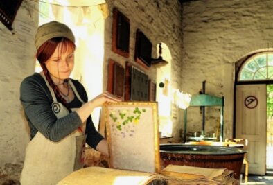 Kunsthandwerker zeigen ihre Arbeit - Beim Tag des traditionellen Handwerks im Erzgebirge ist auch die Papiermühle Niederzwönitz dabei - bereits zum 23. Male. Auf dem Foto präsentiert eine Mitarbeiterin das Handschöpfen von Büttenpapier. 
