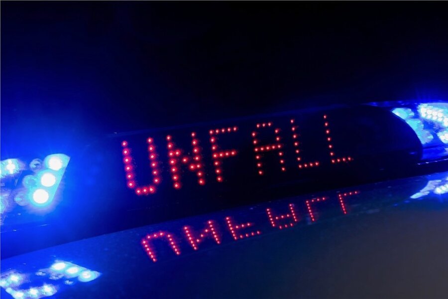 Das Blaulicht auf einem Fahrzeug der Polizei leuchtet in der Dunkelheit, während auf dem Display der Hinweis «Unfall» zu lesen ist. (Symbolbild)