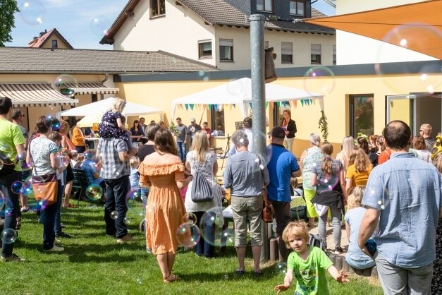 Zum Familienfest anlässlich der Einweihung des Anbaus (rechts) des Kindergartens "Lebensbaum" steigen Seifenblasen in die Luft. 