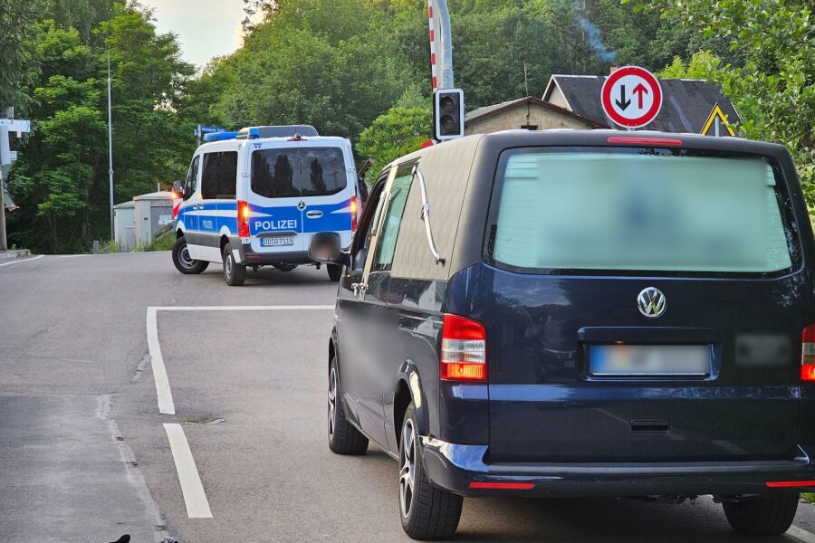 Leichenfund in Döbeln: Ist es die vermisste Valeriia? - Ein Fahrzeug eines Bestattungsunternehmens fährt hinter einem Fahrzeug der Polizei auf einer Straße.