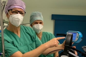 Mandy Büttner und Almut Trapp erklären einem Patienten, wie die Happymedbrille anzuwenden ist. 