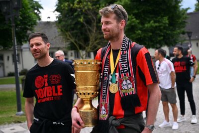 Leverkusener nach kurzer Nacht zurück: Wunderschön gefeiert - Leverkusens Trainer Xabi Alonso (l) und Leverkusens Torhüter Lukas Hradecky kommen mit dem Pokal zum Schloss Morsbroich, um sich in das Goldene Buch der Stadt einzutragen.