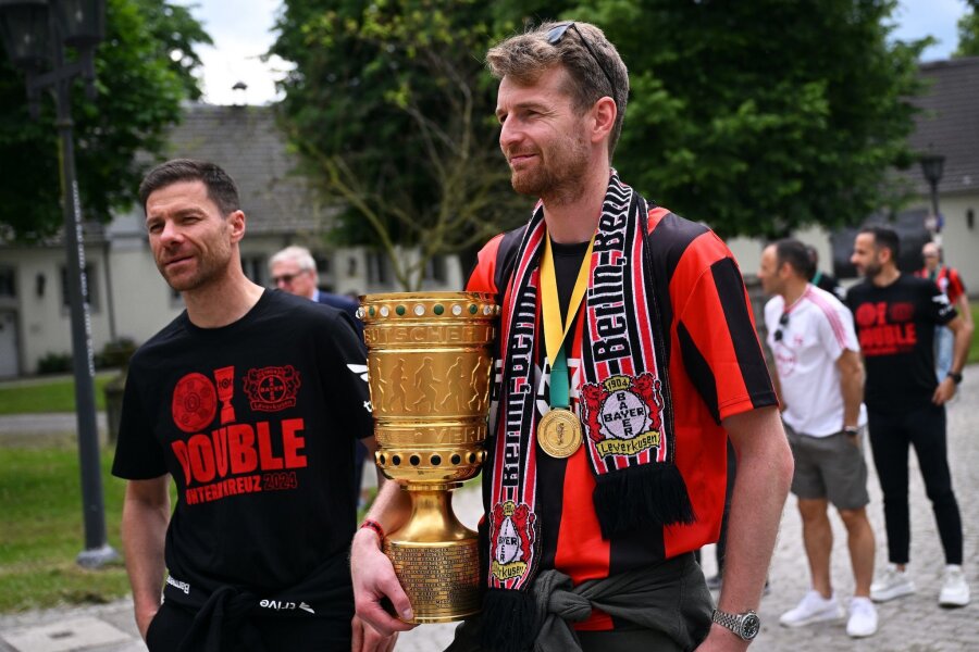 Leverkusener nach kurzer Nacht zurück: Wunderschön gefeiert - Leverkusens Trainer Xabi Alonso (l) und Leverkusens Torhüter Lukas Hradecky kommen mit dem Pokal zum Schloss Morsbroich, um sich in das Goldene Buch der Stadt einzutragen.