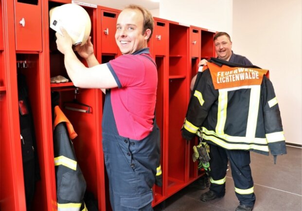 Die Kameraden Tim Heller (vorn links) und Mike Endtmann (r.) räumen im neuen Feuerwehrgeräthaus Lichtenwalde ihre Ausrüstung ein. 