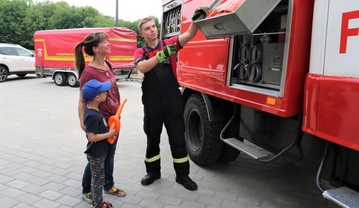 Beim Tag der offenen Tür der Freiwilligen Feuerwehr Lichtenwalde erklärte Julian Anders (r.) Besucherin Michaela Rost (l., mit Sohn Anakin) die Ausstattung des Tanklöschfahrzeugs vom Typ W 50. 