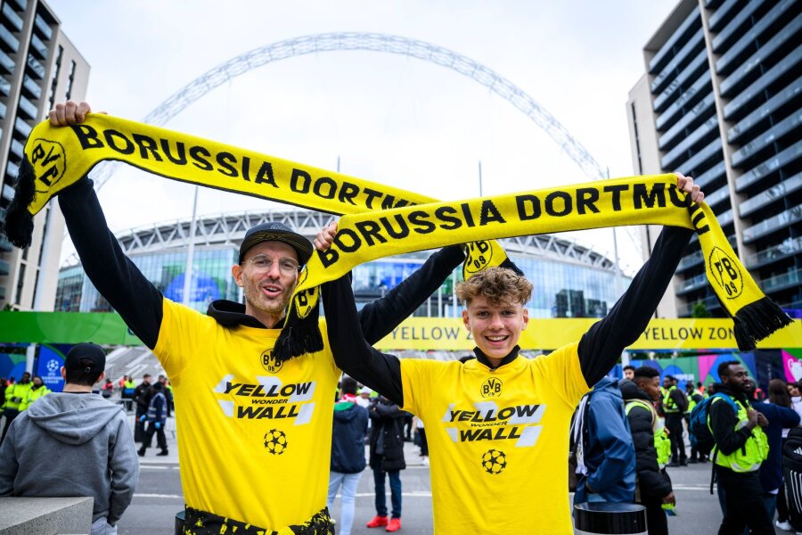 London in gelb-schwarz: BVB-Fans stimmen sich auf Finale ein - Zwei Fans von Borussia Dortmund stehen mit einem BVB-Fan-Schal vor dem Wembley-Stadion.