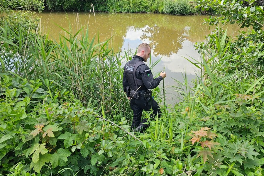 Mädchen in Döbeln verschwunden: Polizei sucht mit Tauchern - Ein Polizist sucht an einem Gewässer in Döbeln nach einem neunjährigen Mädchen.