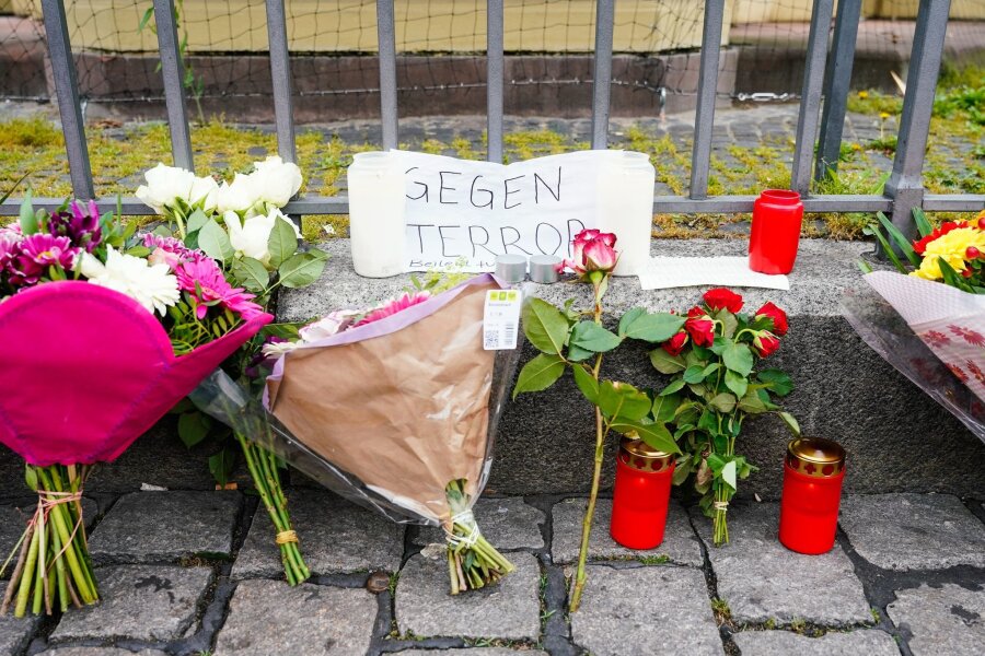 Mahnwache nach Messerangriff - Ermittlungen zu Motiv - Kerzen, Blumen und ein Blatt Papier mit der Aufschrift "Gegen Terror" stehen am Tatort auf dem Mannheimer Marktplatz.