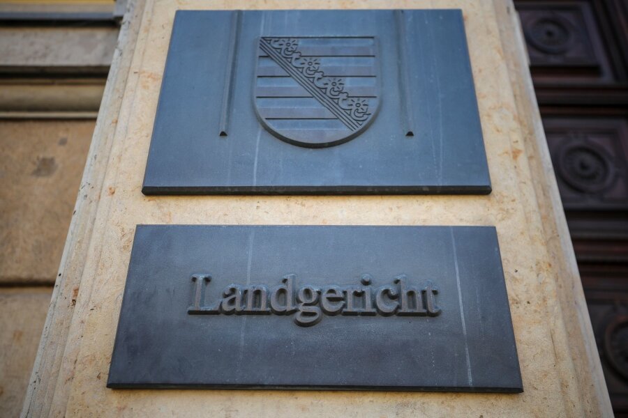 Mann in Speicherruine getötet: 20-Jähriger gesteht - Ein Schild und das sächsische Wappen hängen am Eingang zum Landgericht Leipzig.