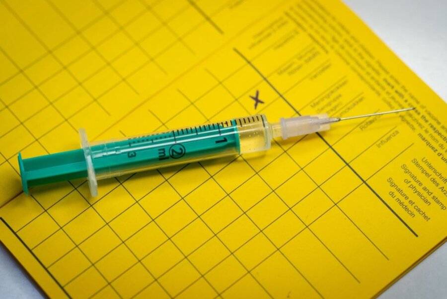 Impfung: Eine Spritze liegt auf einem Impfpass.