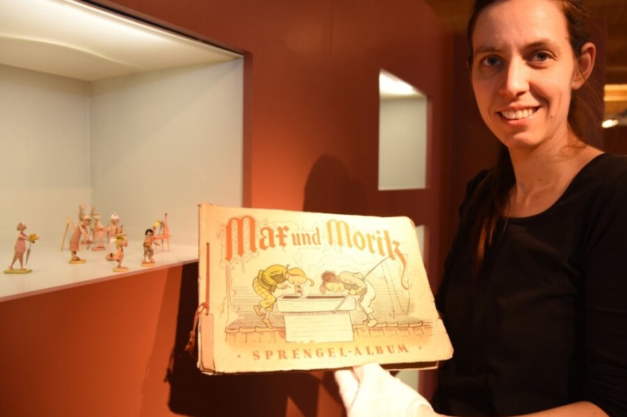 Max und Moritz auf Oelsnitzer Schloss - Museumsleiterin Tina Reitz zeigt ein historisches Sammelbilder-Album zu Max und Moritz. Es ist in der Sonderausstellung über Wilhelm Busch zu sehen. 