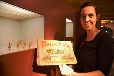 Max und Moritz erobern Schloss Voigtsberg - Museumsleiterin Tina Reitz zeigt ein historisches Sammelbilder-Album zu Max und Moritz. Es ist in der Sonderausstellung über Wilhelm Busch zu sehen. 