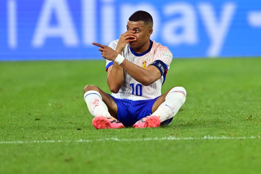 Mbappé hat's erwischt: Wie Nasenbeinbrüche behandelt werden - Diagnose Nasenbeinbruch: Frankreichs Kylian Mbappé sitzt beim Spiel gegen Österreich auf dem Rasen und hält seine verletzte Nase.