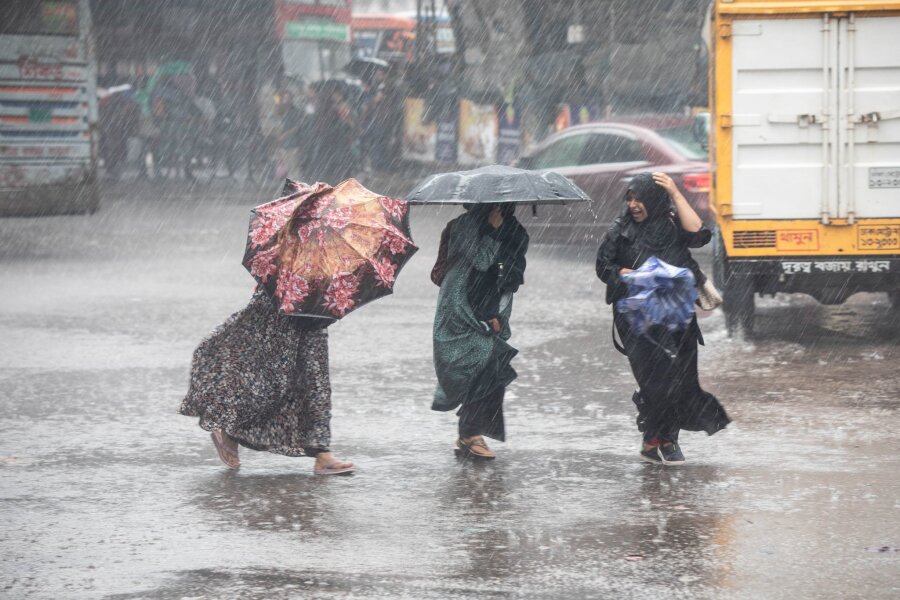 Mehr als 30 Tote bei Wirbelsturm in Südasien - Frauen gehen bei Regen über eine Straße in Bangladesch.
