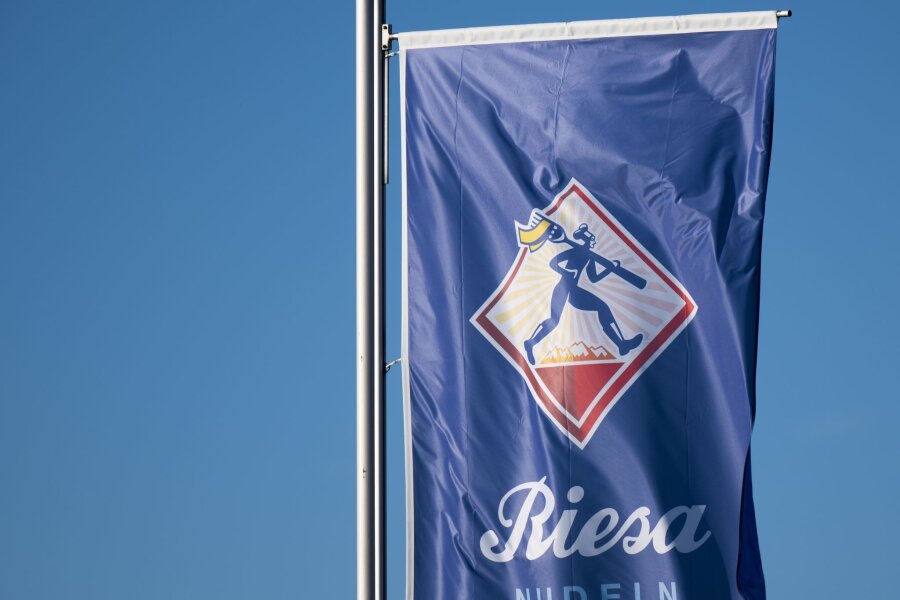 Mehr Geld für Beschäftigte von Riesa Nudeln - Eine Fahne mit dem Logo der Teigwaren GmbH weht vor dem Werk im Wind.