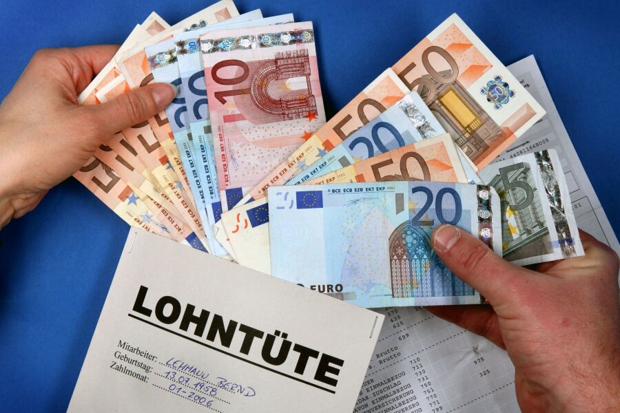 Mehr Geld im Portemonnaie - Zwei Hände stecken symbolisch in Schwerin Euro-Geldscheine in eine Lohntüte.