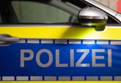 Mehrere mutmaßliche Straftaten: Durchsuchungen in Chemnitz - „Polizei“ ist auf der Tür eines Polizeiautos zu lesen.
