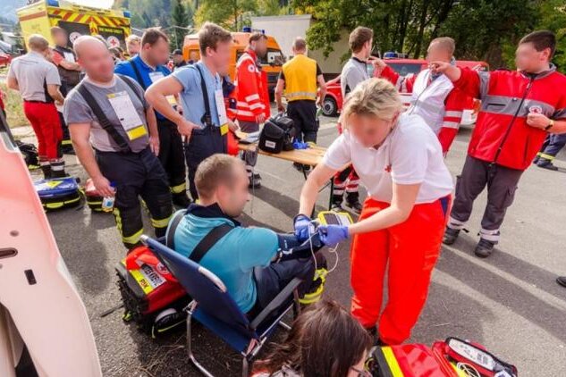 Mehrere Schwerverletzte bei Feuerwehreinsatz in Rothenthal - Einsatzkräfte des Rettungs- und Katastrophendienstes checken die am Brandbekämpfungseinsatz beteiligten Feuerwehrleute und Polizeibeamten auf dem Hof durch.