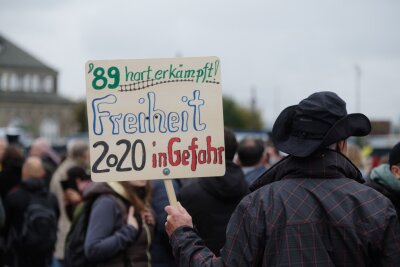 Ein Teilnehmer einer Demonstration der Bewegung "Querdenken 351" trägt ein Schild auf dem Theaterplatz. Viele Menschen protestierten gegen die Coronapolitik der Bunderegierung.