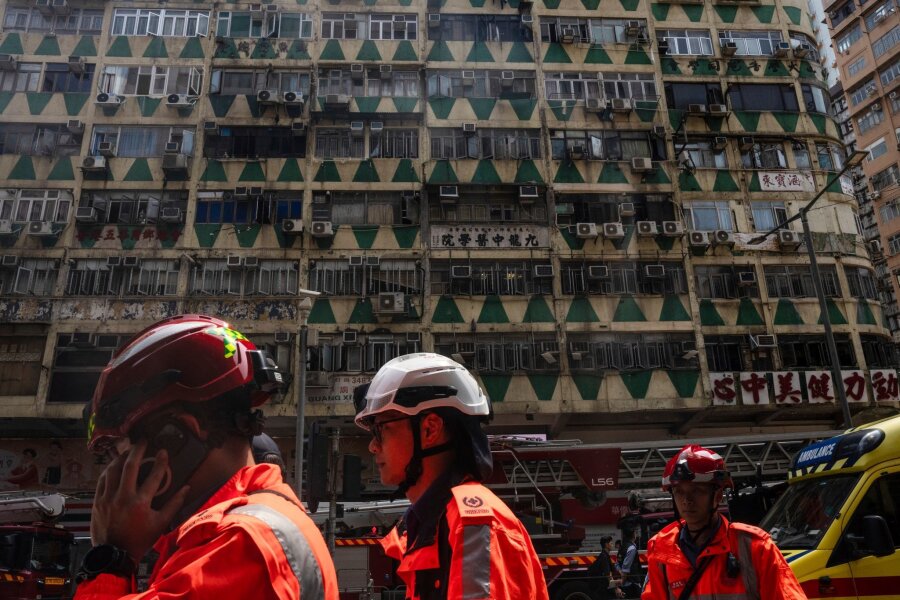 Mehrere Tote bei Hochhausbrand in Hongkong - Im Hintergrund ist das ausgebrannte Hochhaus in Hongkong zu sehen - bei der Feuerwehr waren zahlreiche Hilferufe eingegangen.
