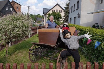 Micheln hat sich für Fest herausgeputzt - Landwirt Bernd Leithold freut sich, dass seine Enkelin Isabell alte Kutschen aus der Scheune geholt und mit Puppen im Vorgarten arrangiert hat.