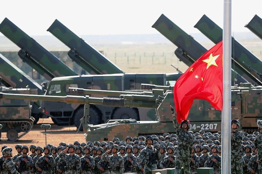 Zur Militärparade zum 90. Geburtstag der Volksbefreiungsarmee auf der Zhurihe Trainings-Basis, 400 Kilometer nordwestlich von Peking, im Jahr 2017 wurde eine Fahne gehisst. Im Hintergrund sind Haubitzen und Raketenwerfer zu sehen. 