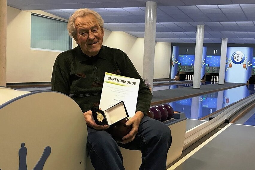 Lothar Wötzel, ausnahmsweise mal nicht in Sportkleidung auf der Bärensteiner Kegelbahn. Der 90-Jährige, ältester Aktiver im Erzgebirgskreis, präsentiert stolz seine Ehrenplakette mitsamt der Urkunde. 