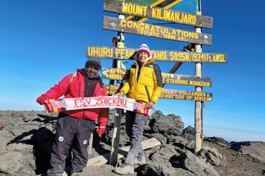 Andrea Herold und Bergführer Jackie halten auf dem Kilimandscharo den Schal in die Kamera. 