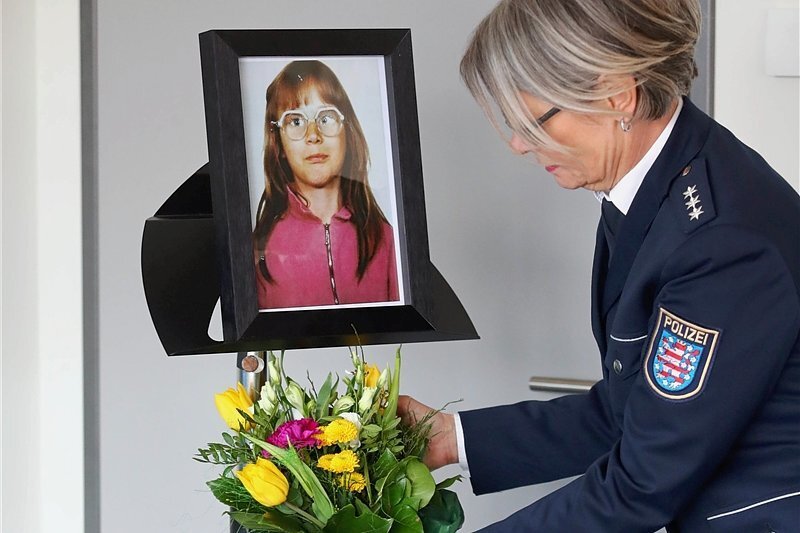 Mühevolle Puzzlearbeit führt im Fall Stephanie zum Erfolg - Vor der Pressekonferenz in Jena stellt eine Polizistin Blumen unter das Foto des Mädchens, das 1991 ermordet wurde.