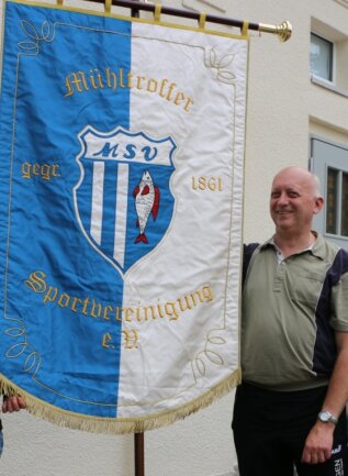 Vereinsvorsitzender Karl-Heinz Lindner zeigt die neue Vereinsfahne, die der Mühltroffer Sportverein vor fünf Jahren einweihte. 