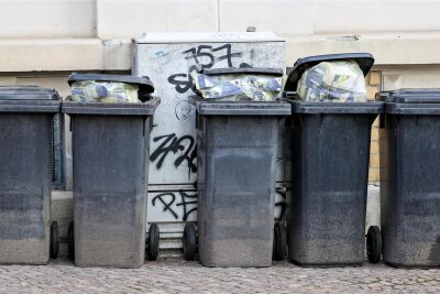 Müllgebühren in Mittelsachsen sollen steigen - Volle Mülltonnen für Restmüll stehen an einer Hauswand (Symbolbild). Ab Januar 2024 sollen die Müllgebühren in Mittelsachsen steigen.