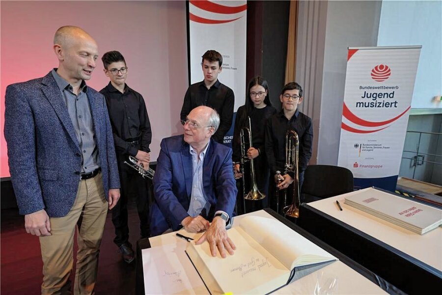 Musikwettbewerb: Ein Präsident besucht Meerane - Martin Maria Krüger trägt sich ins Goldene Buch ein. Rathauschef Jörg Schmeißer (l.) und Schüler schauen zu. 
