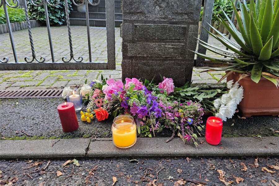 Mutmaßlicher Dreifachmord in Tirpersdorf: Jetzt steht das Obduktionsergebnis fest - Blumen und Kerzen liegen auf dem Boden und erinnern an die Opfer des Gewaltverbrechens. Jetzt ist klar, wie sie gestorben sind.