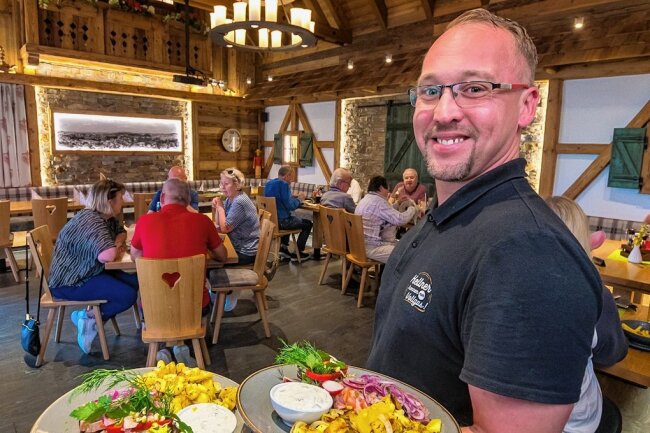 Nach Ausstrahlung von "Mein Lokal, Dein Lokal": Holzwurm in Seiffen erlebt Gästeandrang - Mitarbeiter Dirk Hommel serviert Gästen des "Holzwurms" zwei Hauptgerichte. 