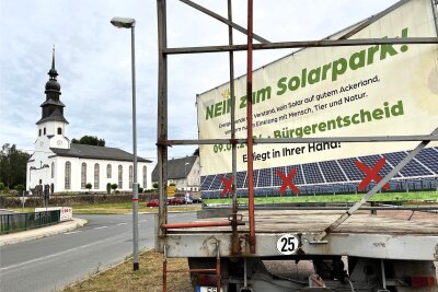 Nach Bürgerentscheid: Solarpark sorgt weiterhin für Ärger in Kriebstein - In Grünlichtenberg war das Nein zum Solarpark auch noch am Montagabend auf diesem Anhänger zwischen Kirche und Schule zu sehen.