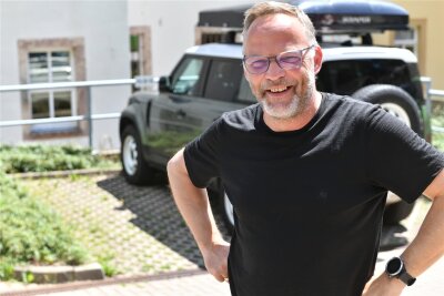 Nach Dienstwagen-Debatte: Mittelsachsens Landrat Dirk Neubauer gibt seinen Geländewagen ab - Dirk Neubauer 2022 mit seinem Auto am Parkplatz Rathaus Augustusburg. Der Land Rover wurde jetzt durch einen Pkw mit Elektromotor abgelöst.