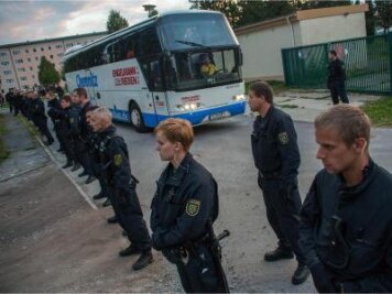 Nach Krawallen Flüchtlingsunterkunft Bischofswerda unter Aufsicht - Polizisten stehen vor einem Bus, der Flüchtlinge in eine Notunterkunft bringt.
