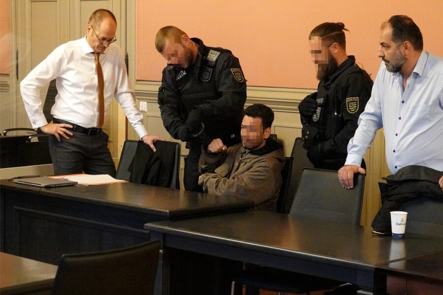 Nach Mord von Crimmitschau: Lebenslange Haftstrafe für Ehemann des Opfers - Justizbeamte bewachten den Angeklagten (Mitte) im Gerichtssaal.