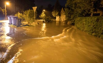 Nach Überflutung in Freiberg: Warum blieb die Warnapp stumm? - Der Münzbach trat über die Ufer und verwandelte die Straße in einen Fluss. Das schlammige Wasser überspülte Grundstücke und drang in Gebäude ein.