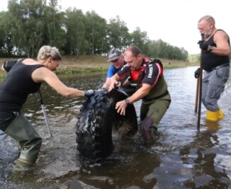 Naturschützer befreien Mulde von alten Reifen - Schweißtreibende Sache: Andreas Trautmann (2. von links) und seine Helfer bugsieren einen Reifen aus der Mulde. 
