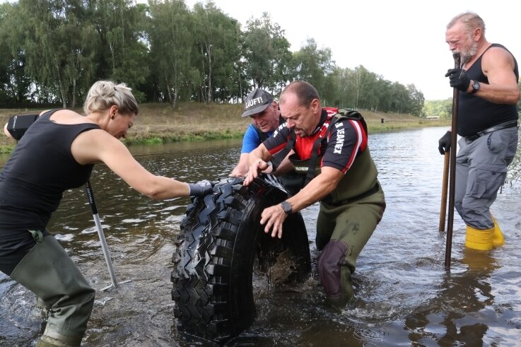 Naturschützer befreien Mulde von alten Reifen - Schweißtreibende Sache: Andreas Trautmann (2. von links) und seine Helfer bugsieren einen Reifen aus der Mulde. 