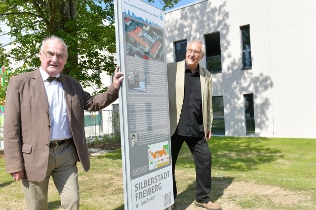 Professor Gottfried Jäckel (links) und Jürgen Bellmann vom Freiberger Altertumsverein an der Stele für das einstige Forschungsinstitut für Nichteisenmetalle an der Lessingstraße. Beide waren früher hier tätig. 