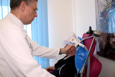 Neue Therapie am Erzgebirgsklinikum: Wie Magnetimpulse gegen Depression helfen - Oberarzt Thomas Heinze bereitet im Zschopauer Krankenhaus einen Patienten für eine RTMS-Sitzung vor.