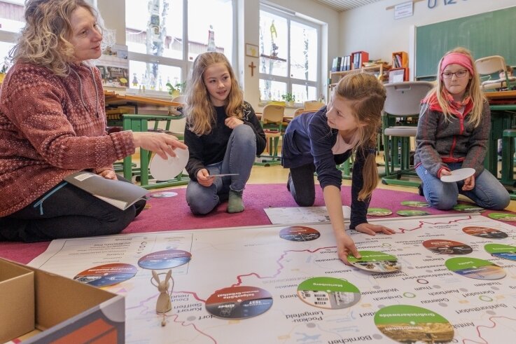Lehrerin Ariane Grund (links) von der Montessori-Grundschule in Annaberg hat das neue Lernspiel mit entwickelt. Einem ersten Test haben es Julika, Ella und Larissa (von links) von den "Wüstenfüchsen" unterzogen. 