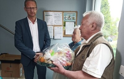 Neues Zuhause für Ukrainer - Tatjana und Leonid Lapin werden im Flur vom Geschäftsführer der Gebäudegesellschaft Limbach-Oberfrohna, Norbert Gruss, zum Einzug in ihre neue Wohnung mit einem Obstkorb begrüßt. 
