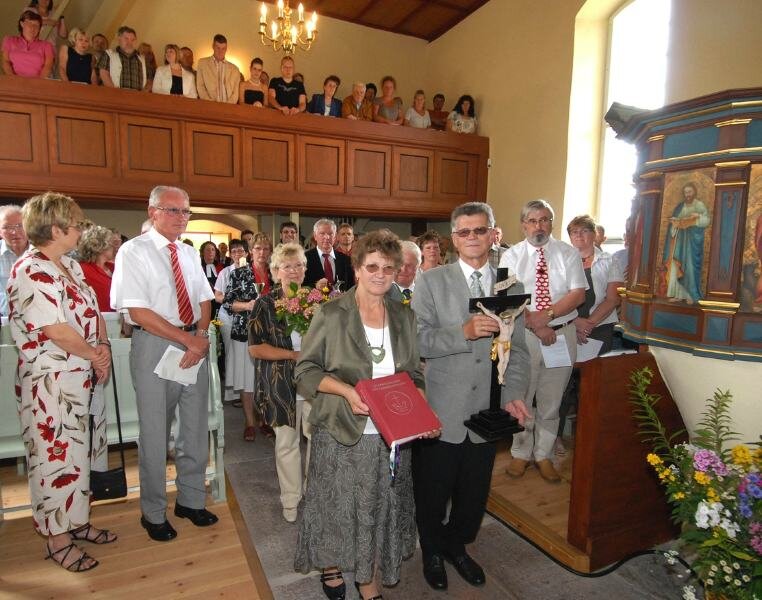 
              <p class="artikelinhalt">Sieglinde und Roland Gentsch tragen das Gottesdienstbuch und das Kreuz zum Altar der wieder eingeweihten Dorfkirche.</p>
            