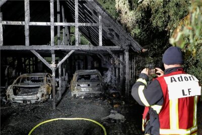 Ein Adorfer Feuerwehrmann fotografiert den ausgebrannten Doppelcarport an der Forststraße in Neukirchen.