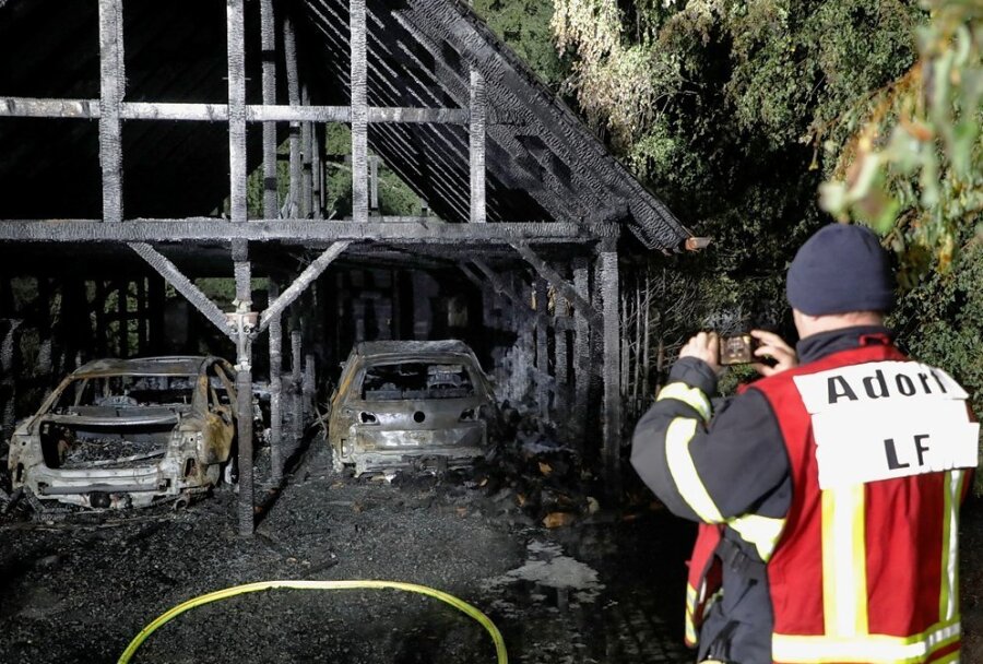 Ein Adorfer Feuerwehrmann fotografiert den ausgebrannten Doppelcarport an der Forststraße in Neukirchen.