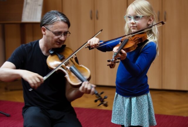 Die siebenjährige Edith aus Plauen probierte am Samstag hoch konzentriert eine Kindergeige aus. Musikpädagoge Torsten Trommer zeigte sanft, wie die Saiten gestrichen werden. 