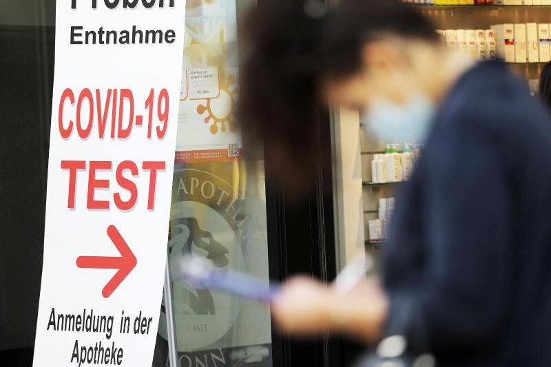            Eine Frau füllt vor einer Apotheke in Bonn ein Formular für einen Covid-19-Test aus.